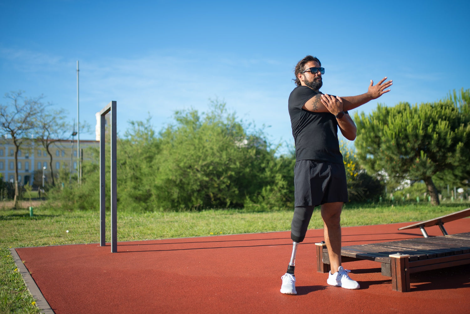 A man with a prosthetic right leg stretching in a park