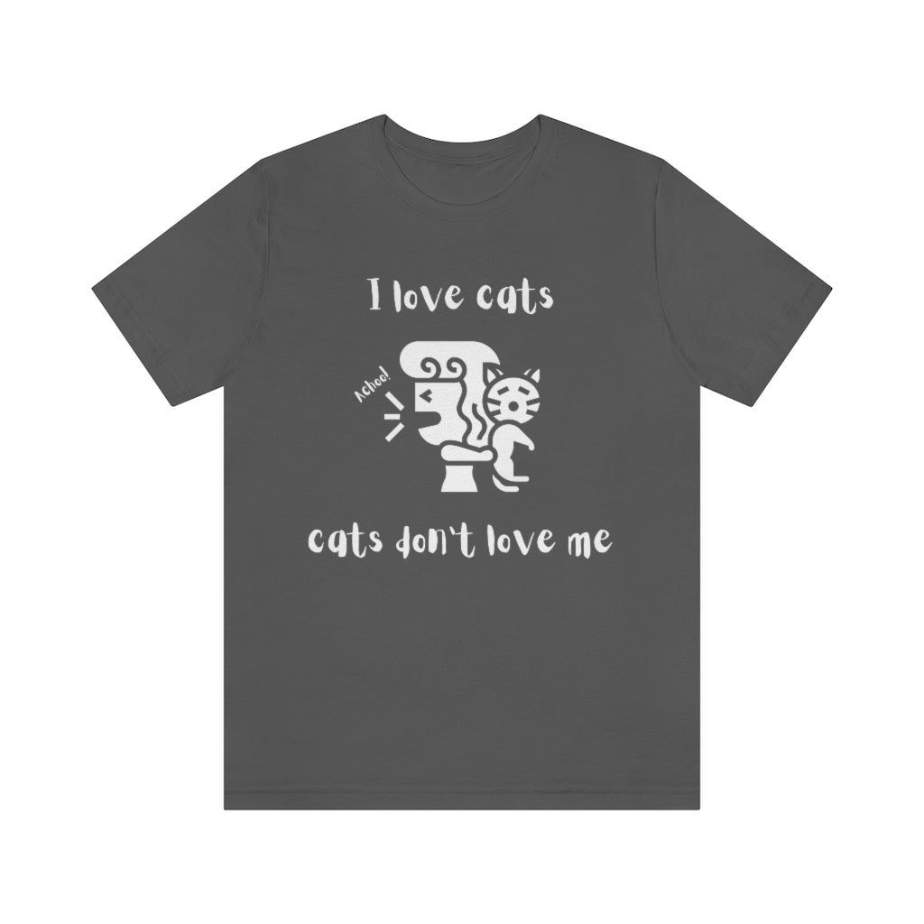 An asphalt colored t-shirt showing a woman looking away from a cat sneezing, with the text "I love cats, cats don't love me"