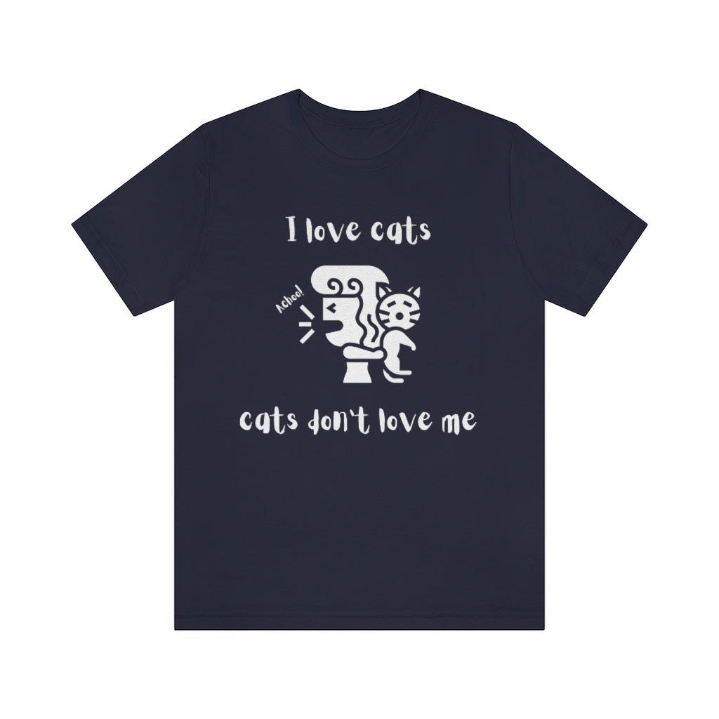 A navy colored t-shirt showing a woman looking away from a cat sneezing, with the text "I love cats, cats don't love me"
