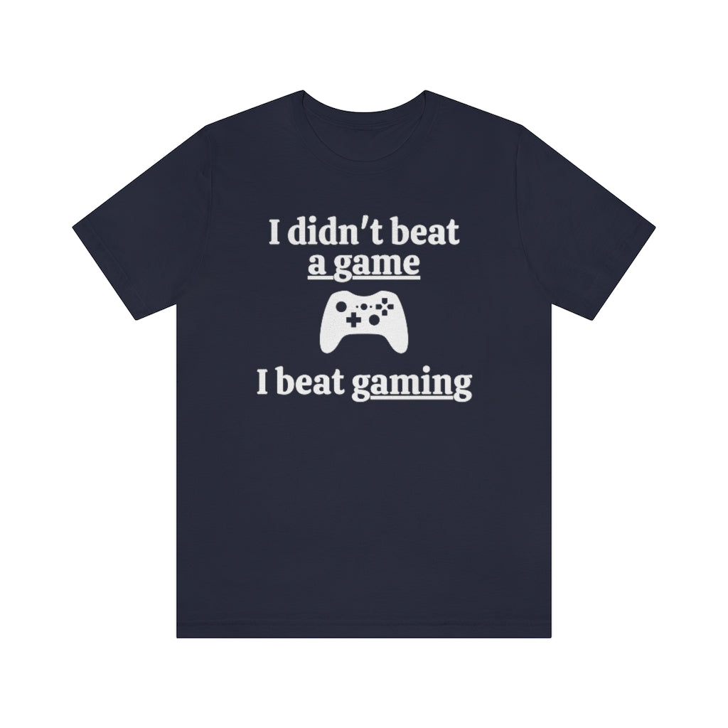 Navy t-shirt with white text saying "I didn't beat a game, I beat gaming". With an iamge of an xbox controller in the middle.