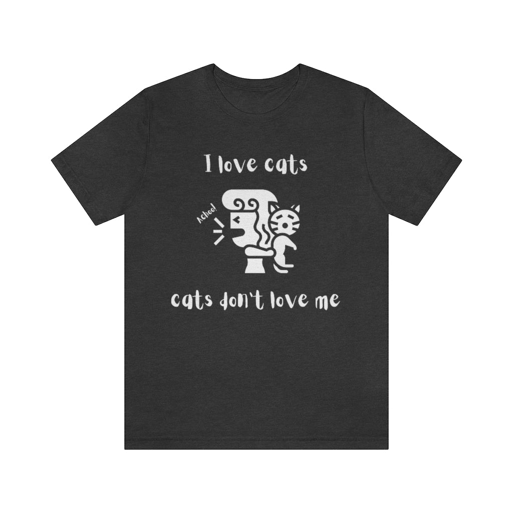 A dark gray heather colored t-shirt showing a woman looking away from a cat sneezing, with the text "I love cats, cats don't love me"