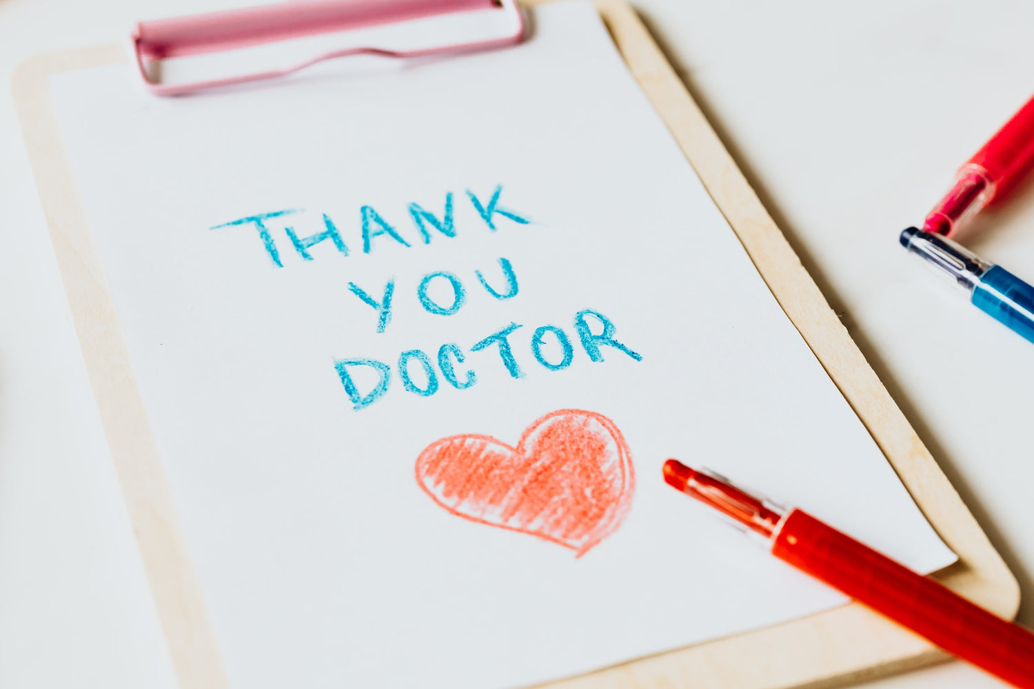A clipboard with the text, in crayong, "Thank you doctor" and a heart drawn under it