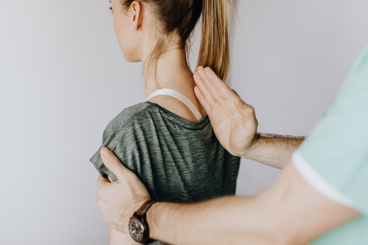 A young woman is getting her spine checked with a man's hand