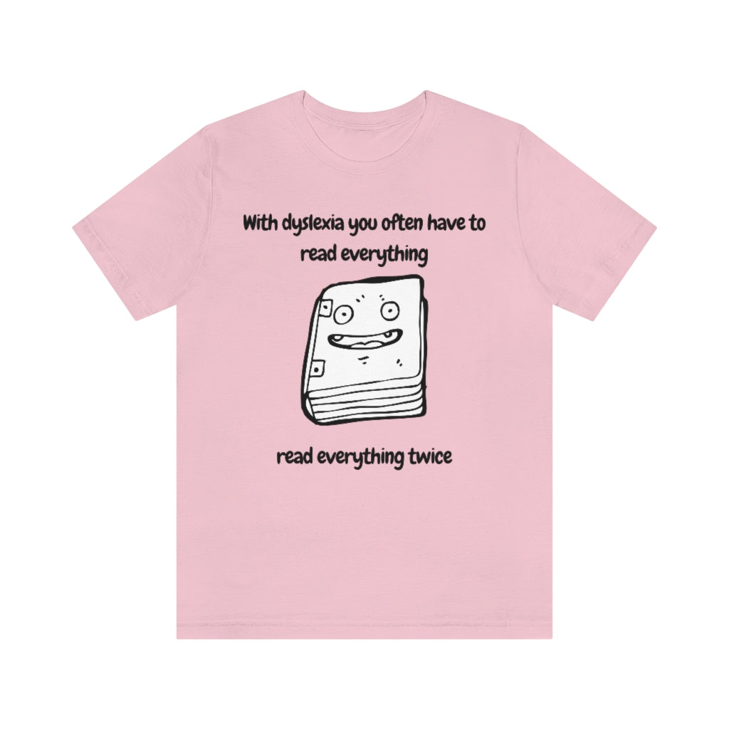 A pink t-shirt with a smiling drawing of book on it, with the text: "With dyslexia you often have to read - read everything twice".