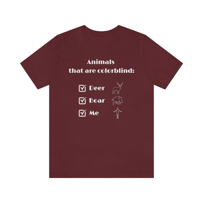 A maroon colored T-shirt with white text reading: "Animals that are colorblind:". Under it are 3 checked boxes with the words "Deer", "Boar" and "Me". Behind these are outline drawings showing the animals and a human.