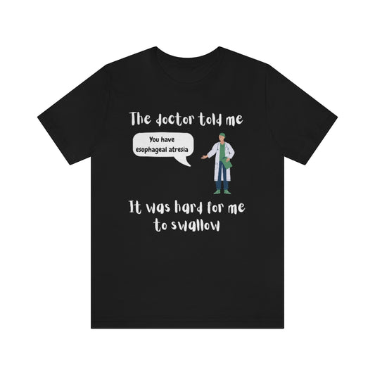 A black shirt with white text saying: "The doctor told me" followed by a surgeon with a text balloon  saying "You have esophageal atresia", followed by text saying: "It was hard for me to swallow".