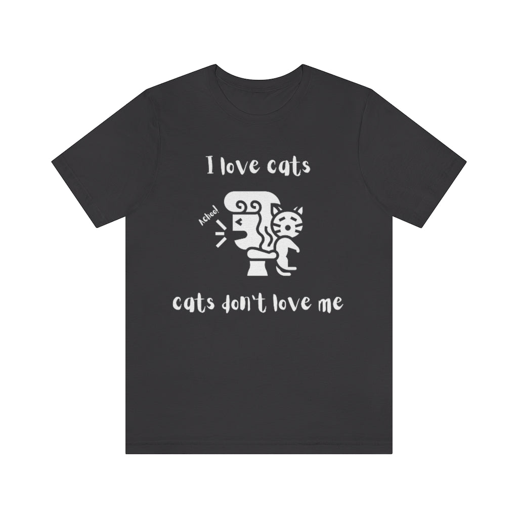 A dark gray t-shirt showing a woman looking away from a cat sneezing, with the text "I love cats, cats don't love me"