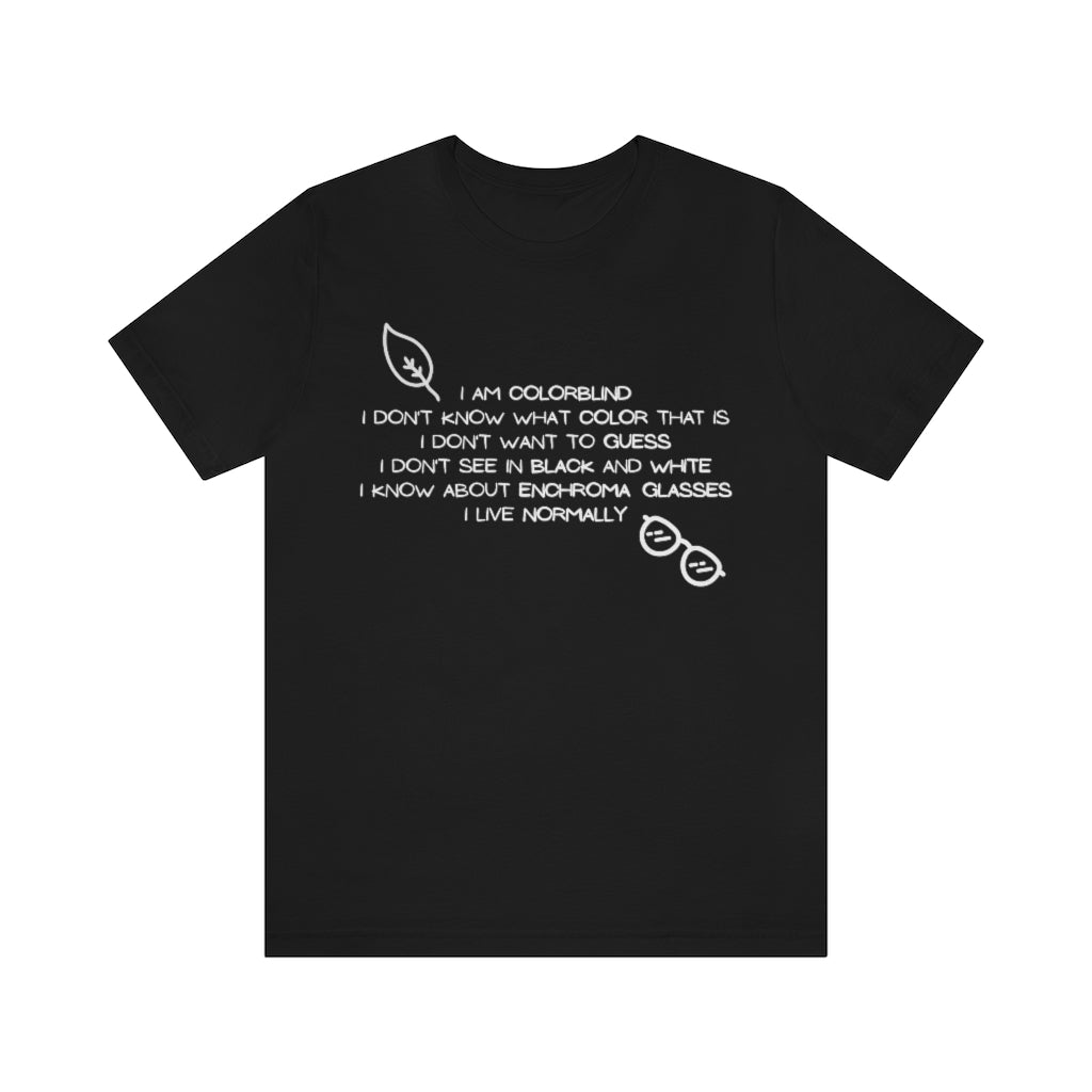 A black t-shirt with white text reading: I am colorblind. I don't know what color that is. I don't want to guess. I don't see in black and white. I know about enchrroma glasses. I live normally. The top left has a drawing of a leaf, the bottomright a pair of sunglasses, both in white.