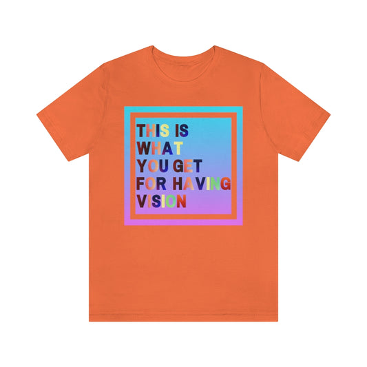 An orange t-shirt with a gradient box with the text "This is what you get for having vision" in multiple clashing colors.