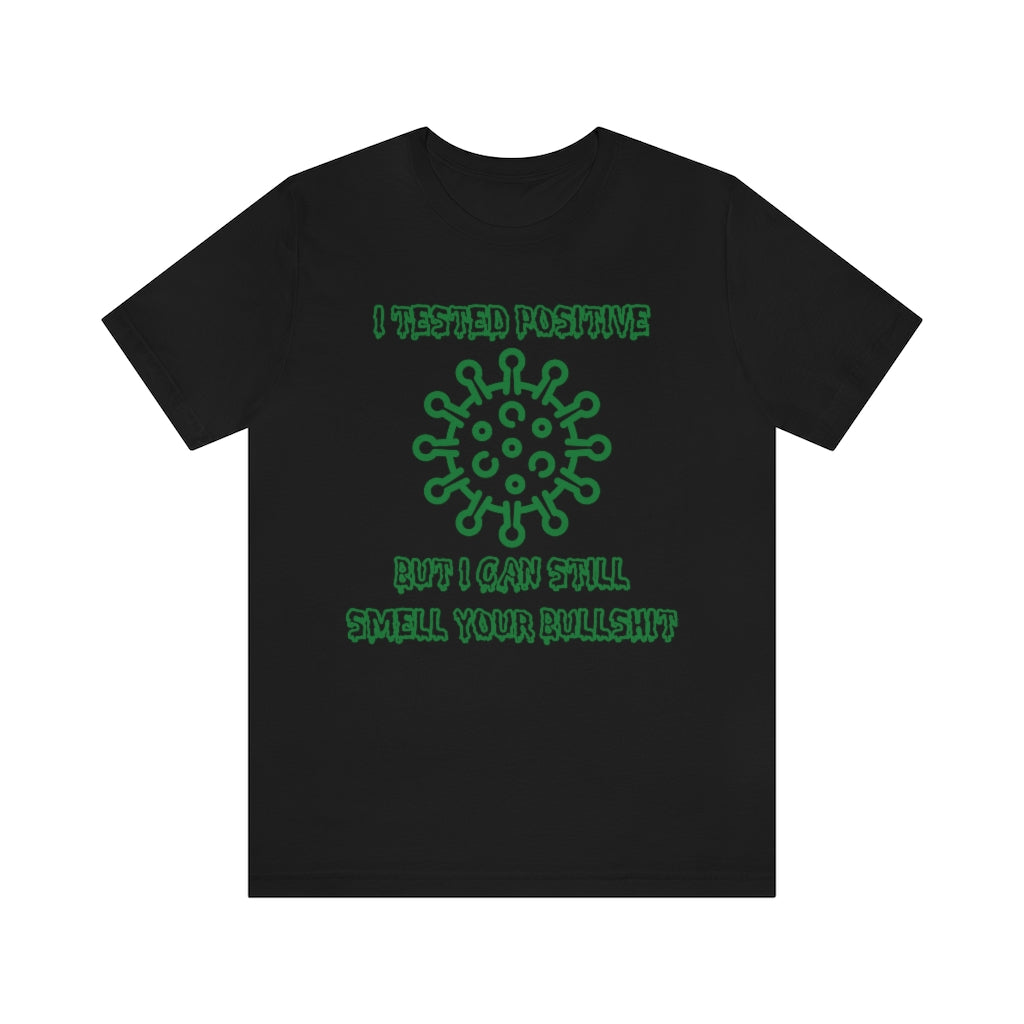 A black t-shirt with green, sickness-dripping text and a corona virus image saying "I tested positive, but I can still smell your bullshit"