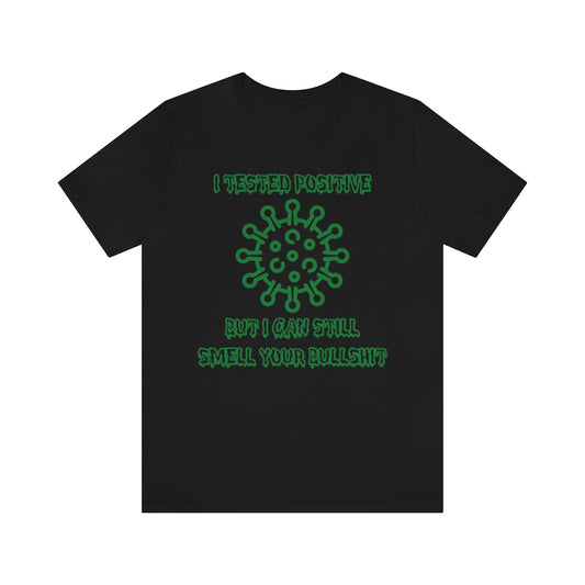 A black t-shirt with green, sickness-dripping text and a corona virus image saying "I tested positive, but I can still smell your bullshit"