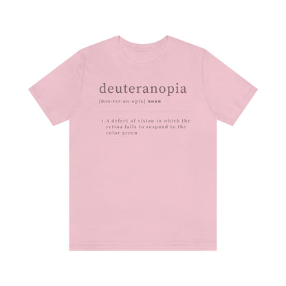 A pink t-shirt with text laid out like a dictionary. It reads in black letters: "Deuteranopia, noun. A defect of vision in which the retina fails to respond to the color green."