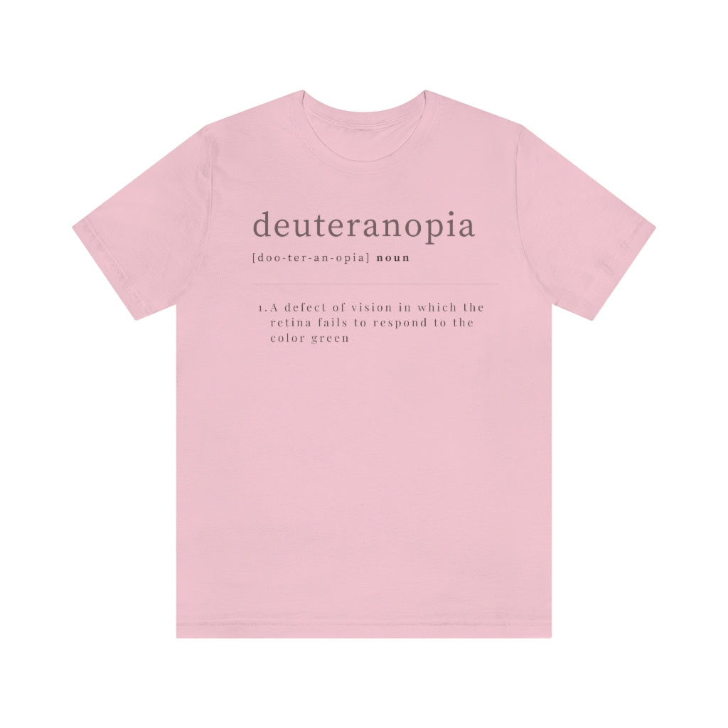 A pink t-shirt with text laid out like a dictionary. It reads in black letters: "Deuteranopia, noun. A defect of vision in which the retina fails to respond to the color green."