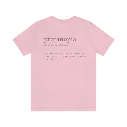 A pink t-shirt with text laid out like a dictionary. It reads in black letters: "protanopia, noun. A defect of vision in which the retina fails to respond to red or green."