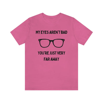 A charity pink t-shirt with black text reading "My eyes aren't bad, you're just very far away" with a pair of glasses in the middle.