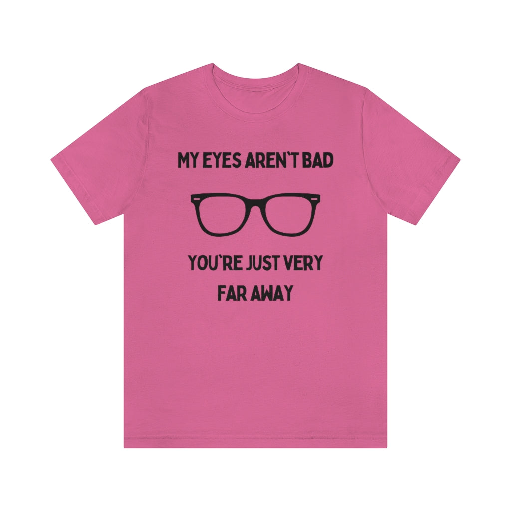 A charity pink t-shirt with black text reading "My eyes aren't bad, you're just very far away" with a pair of glasses in the middle.