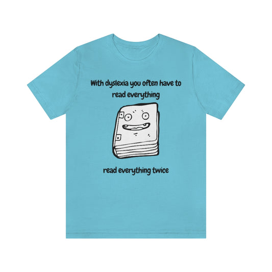 A turquoise t-shirt with a smiling drawing of book on it, with the text: "With dyslexia you often have to read - read everything twice".