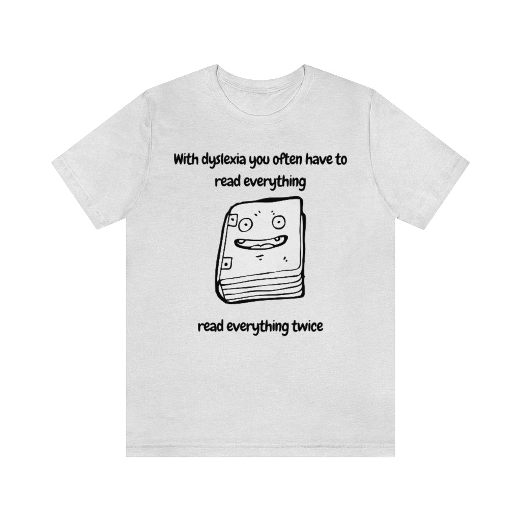 An ash-colored t-shirt with a smiling drawing of book on it, with the text: "With dyslexia you often have to read - read everything twice".